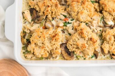Fluffy drop biscuits on top of chicken casserole in a white dish.