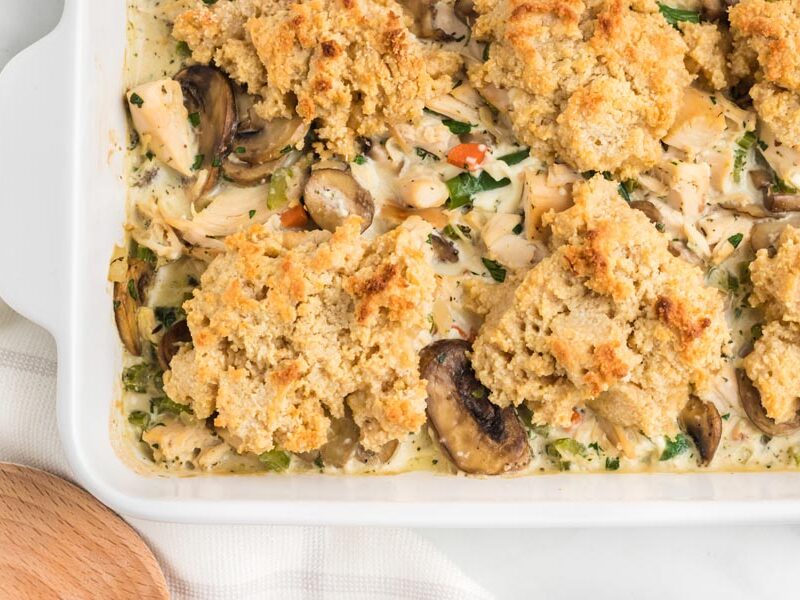 Fluffy drop biscuits on top of chicken casserole in a white dish.
