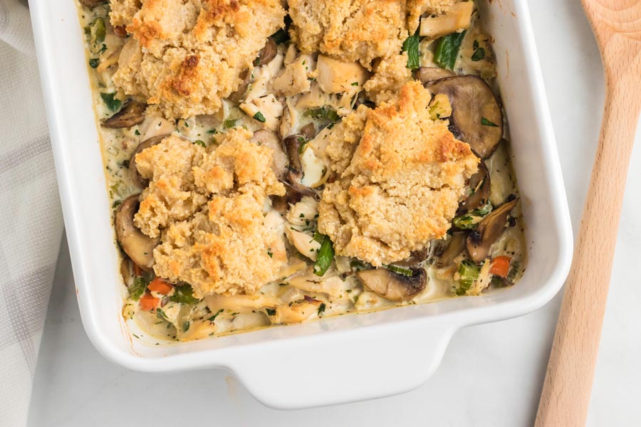 Keto biscuits dropped on top of a creamy chicken and vegetable mixture and baked in a casserole dish.