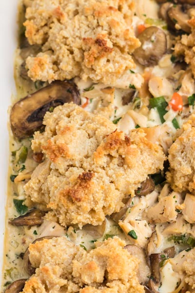 Close up of biscuits baked on top of a creamy chicken casserole mixture with carrot, green bean and mushrooms.