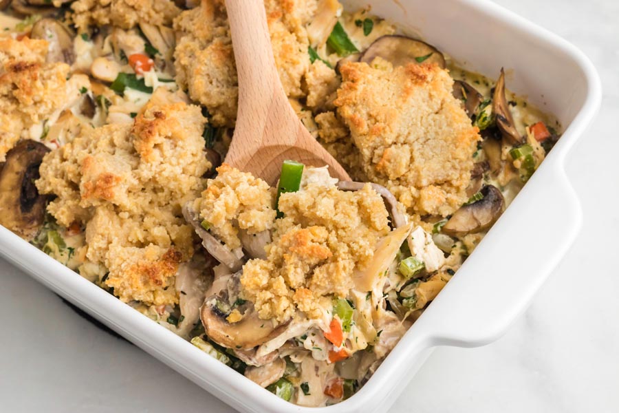 A wooden spoon holds a serving of chicken pot pie casserole.