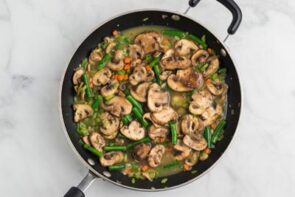 A skillet holding cooked vegetables in chicken broth.