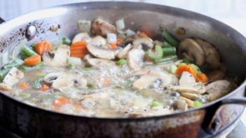 a mixture of mushrooms, carrots and green beans boiling in a skillet