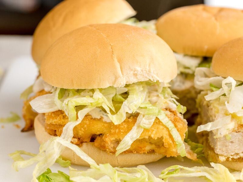 A homemade keto McChicken sandwich with a golden crispy chicken patty, shredded lettuce, pickles, and creamy sauce.