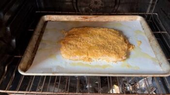 The giant breaded chicken patty baking on a sheet pan until golden brown and crispy.