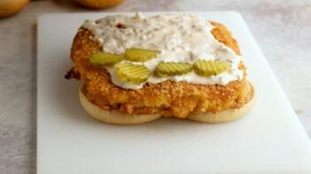 A crispy chicken patty topped with creamy pickle ranch sauce and sliced pickles on a low-carb bun.