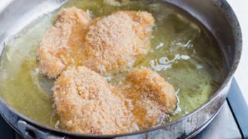 crumb of pork rind sizzling in the skillet with avocado oil