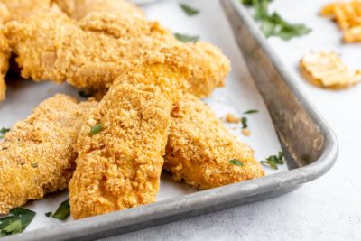 a stack of chicken strips on a tray sprinkled with parsley