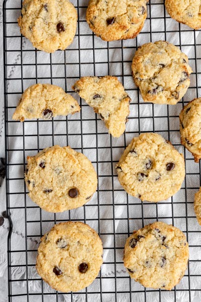 a bunch of chocolate chip cookies on a wire rack with one cook split in half