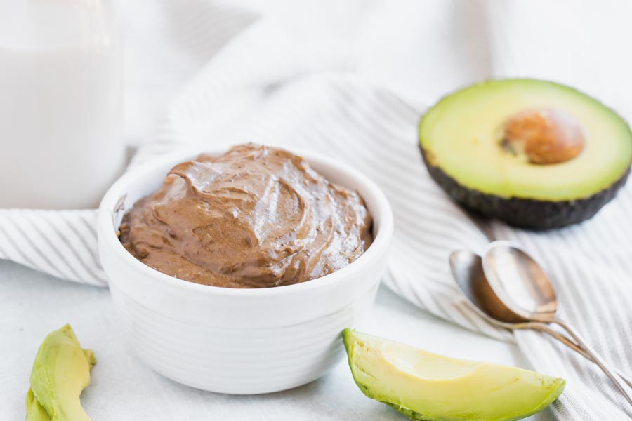 creamy chocolate pudding made with avocados with avocados near by