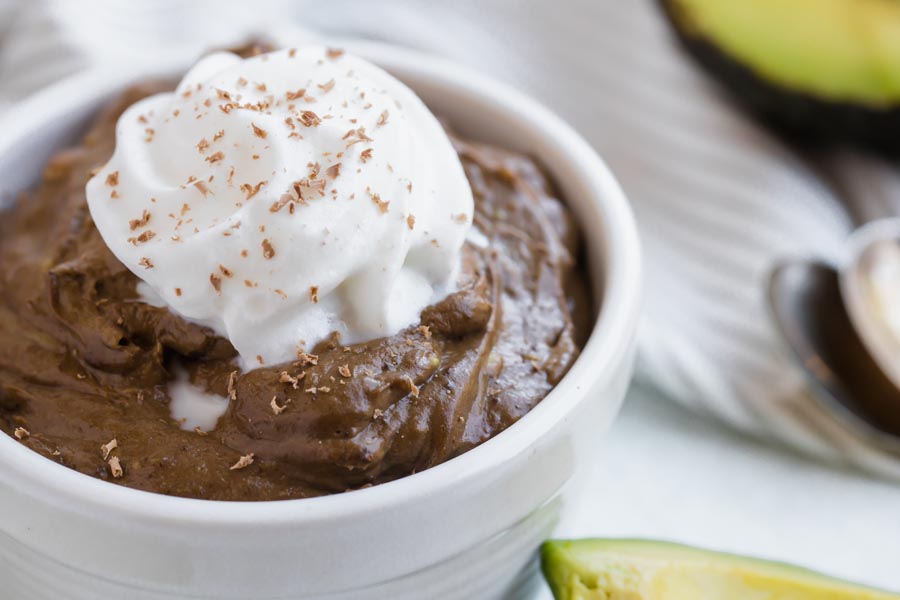 close up of dark chocolate keto pudding topped with whipped cream