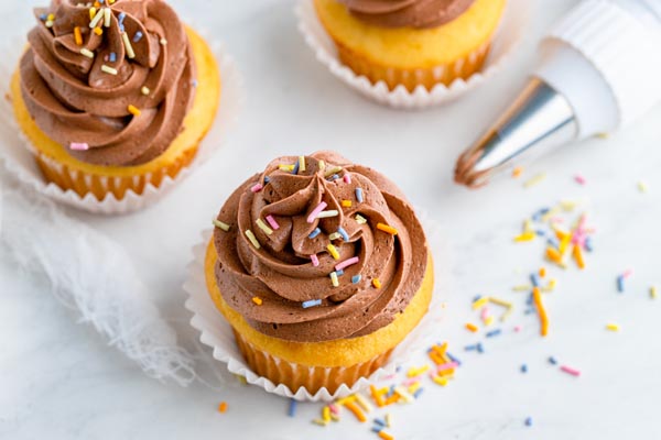 keto chocolate buttercream piped on vanilla cupcakes with spinkles on top