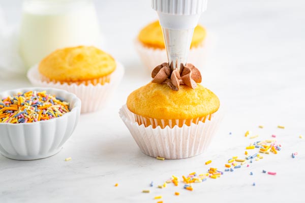 piping chocolate buttercream onto a keto cupcake