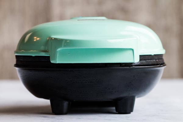 teal waffle maker sitting on a counter