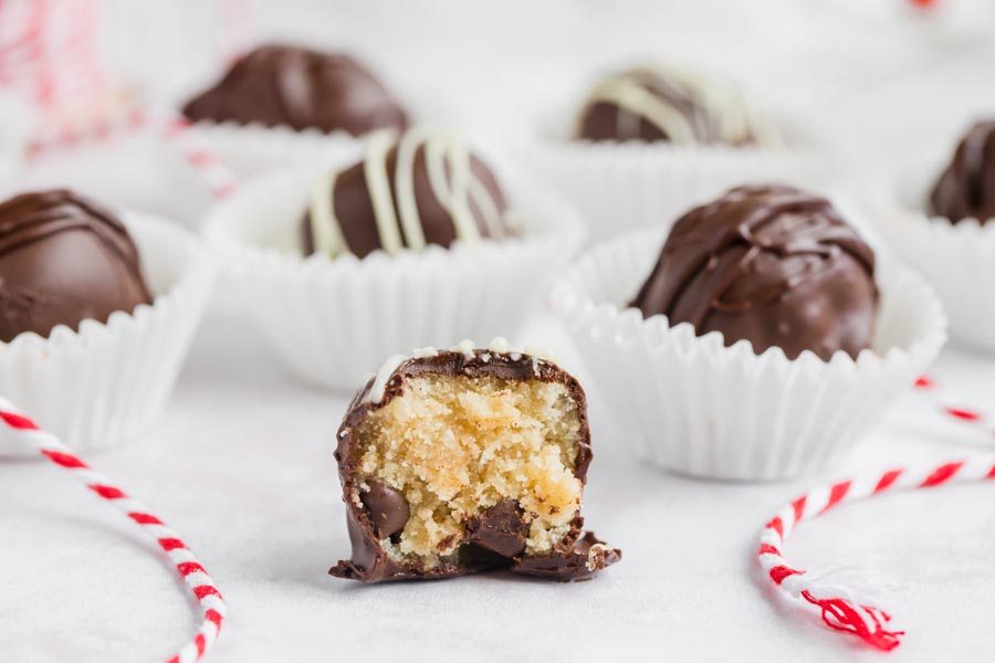 bitten cookie dough keto truffle with red rope around and truffle in the back