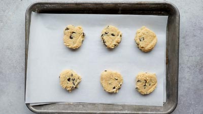 Portions of cookie dough arranged on a baking sheet