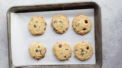 Baked keto chocolate chip cookies on a parchment-lined tray