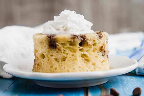 straight on view of chocolate chip mug cake on a blue backboard