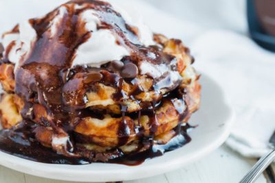 keto chocolate chip waffles topped with chocolate syrup and whipped cream