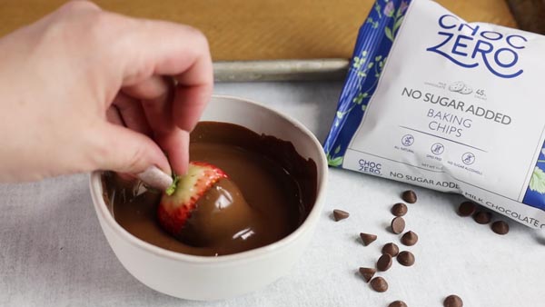 dipping a strawberry in some sugar free melted chocolate
