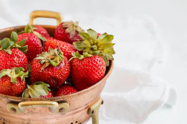 ripe strawberries in a copper collander