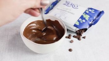 melted keto milk chocolate in a bowl next to sugar free chips
