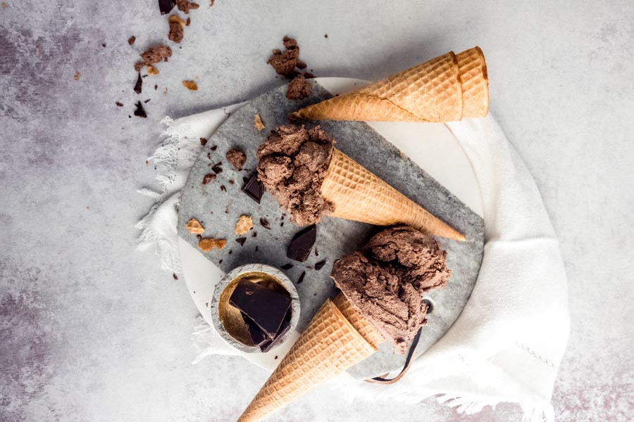 two cones with chocolate ice cream and empty cones stacked together