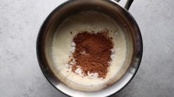 boiling cream in a saucepan with cocoa powder on top