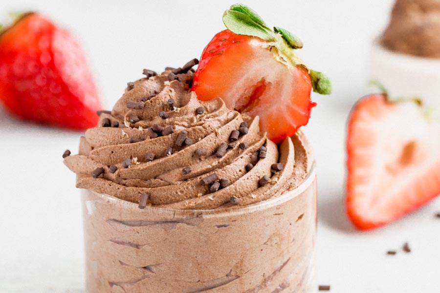creamy chocolate mousse in a small dish topped with sprinkles and strawberries
