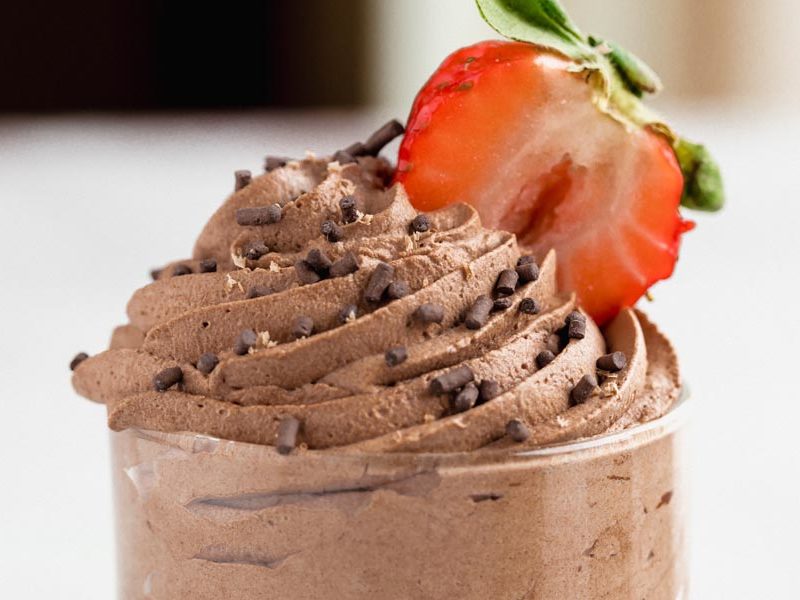 swirlled chocolate mousse coming out of a clear dish with a strawberry slice stuck in the mousse