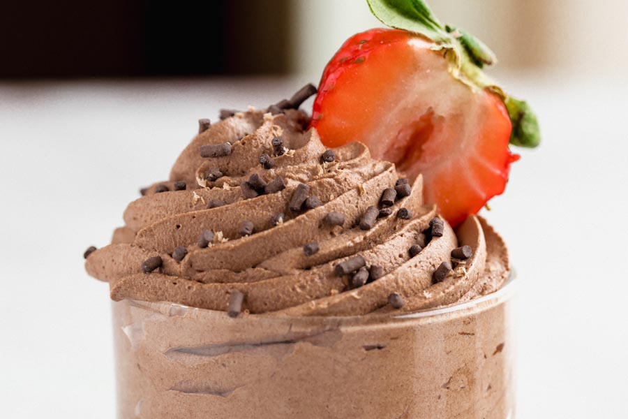 swirlled chocolate mousse coming out of a clear dish with a strawberry slice stuck in the mousse