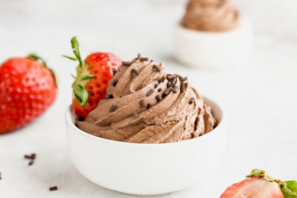 a small white bowl with piped chocolate cream in it and a strawberry