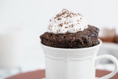 close up of moist keto cake topped with a swirl of whipped cream and chocolate curls