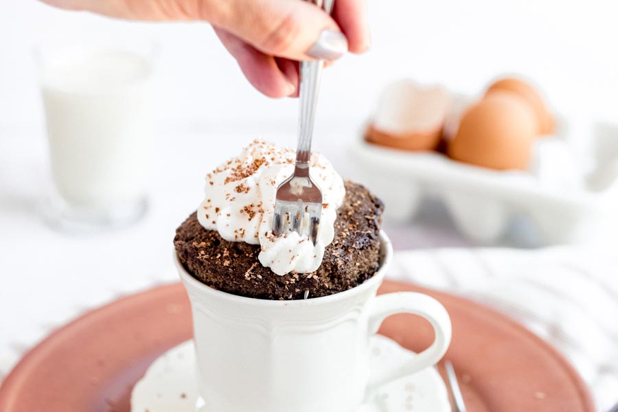 digging into a chocolate mug cake with a small fork