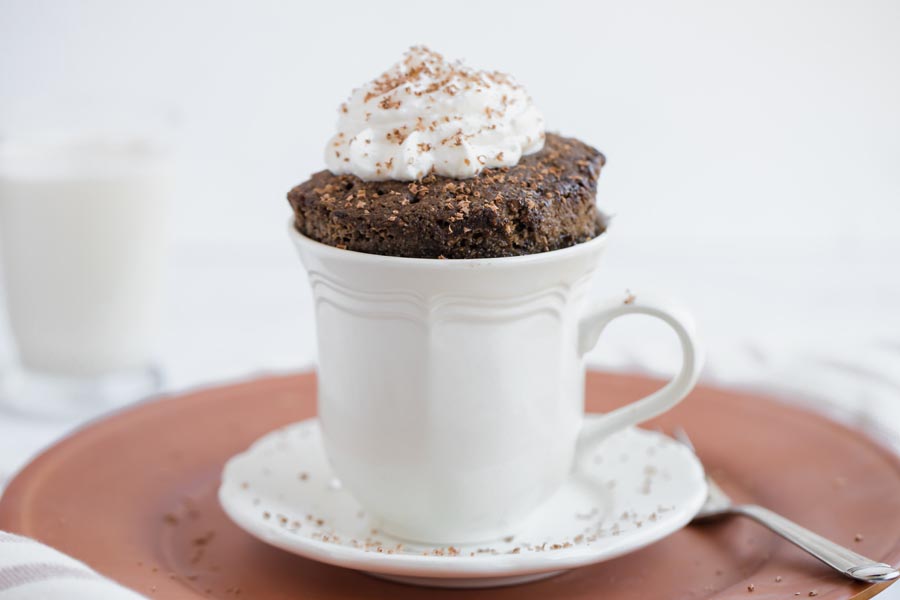 chocolte mug cake topped with whipped cream and chocolate shavings