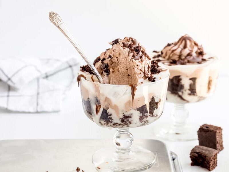 Two glass bowls of chocolate trifle layered with cake and cream, topped with chocolate mousse.