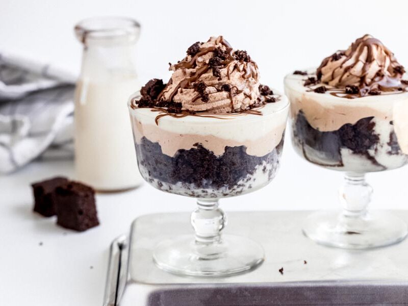 Two chocolate trifles side by side with layers of chocolate cake, chocolate whipped cream and vanilla pudding.