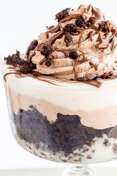 A close up of the layers of a trifle containing vanilla pudding, chocolate cake and chocolate whipped cream.