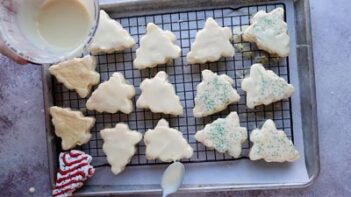 Spooning melted white chocolate on top of small tree cakes.