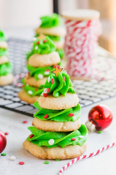 Keto Christmas tree cookies on a wire rack with red and white string draped nearby and a red Christmas bulb.