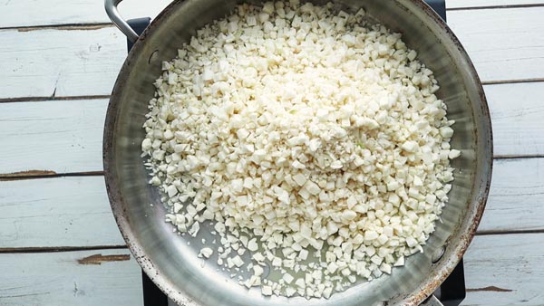 small pieces of riced cauliflower in a skillet