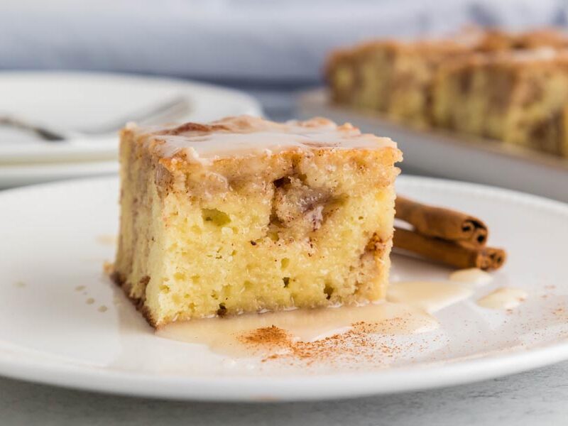 A slice of coffee cake topped with a vanilla glaze and dusted with cinnamon.