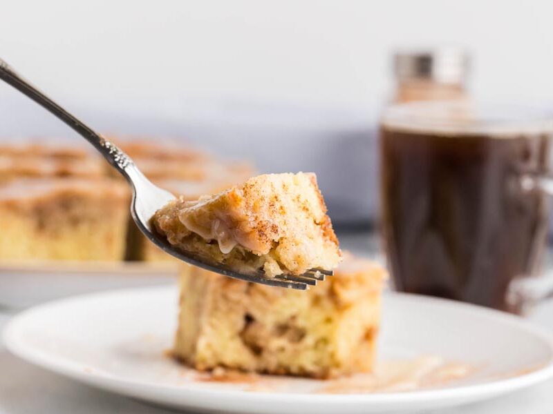 A fork holding a bite of cinnamon coffee cake.