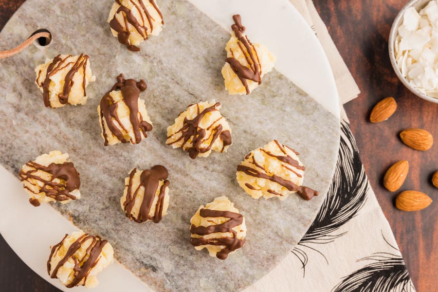 coconut and almond filled candies on a circle plate with whole almonds near