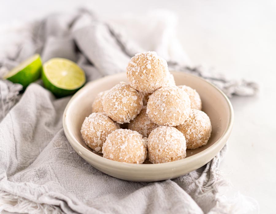 a bowlfull of coconut lime balls with limes sliced in half