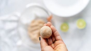 small ball in a hand holding over a bowl