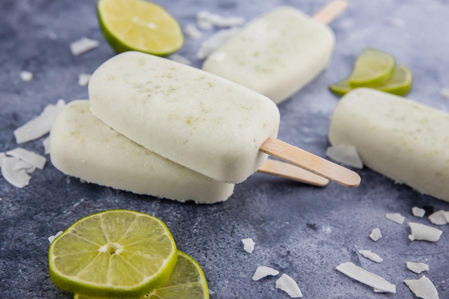 two popsicles on top of each other and halved limes sliced on the counter with a couple of pop near