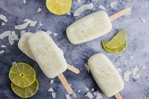ltop down view of three popsicles with whole lime slices and shredded coconut