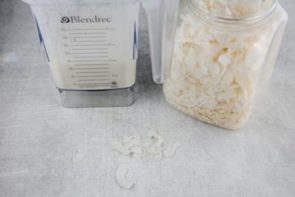 a blender with a creamy popsicle mixture in it and shredded coconut in a container