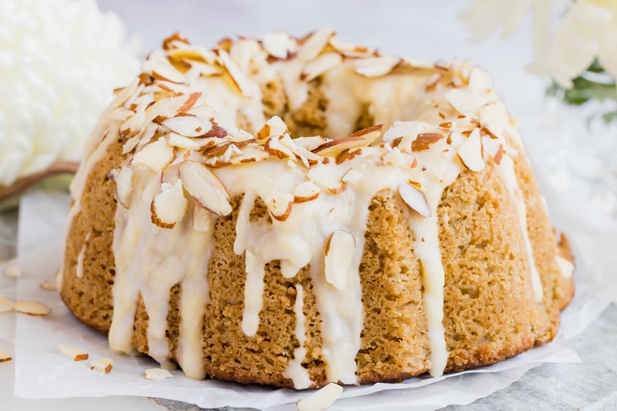 icing drizzled down a coffee bundt cake covered with sliced almonds